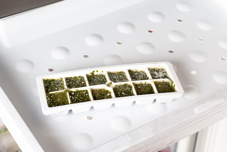 Frozen basil in ice cubes in the freezer. Frozen vegetables. Concept of healthy eating.