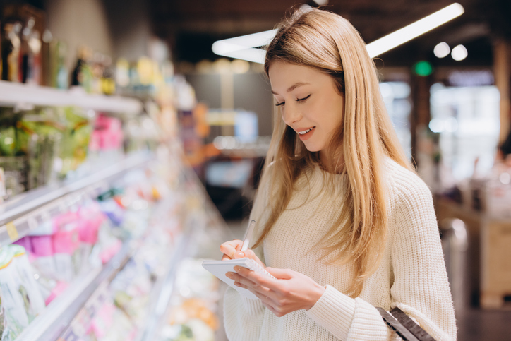 Customer checking shopping list while buying groceries in supermarket