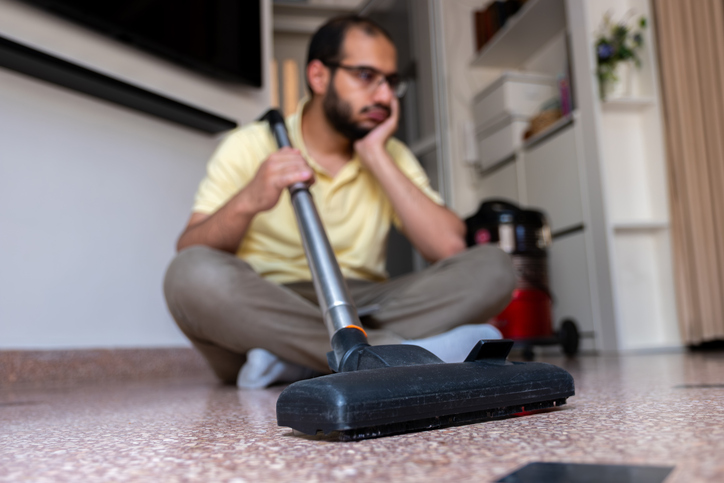 Man Looking Bored While Vacumming Floor at Home