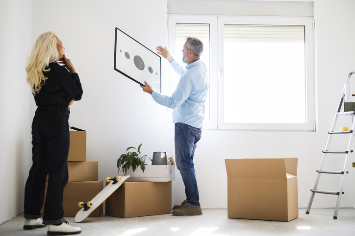 Couple Hanging Poster On Wall At Home