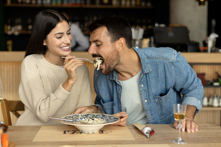Loving couple eating spaghetti at the restaurant