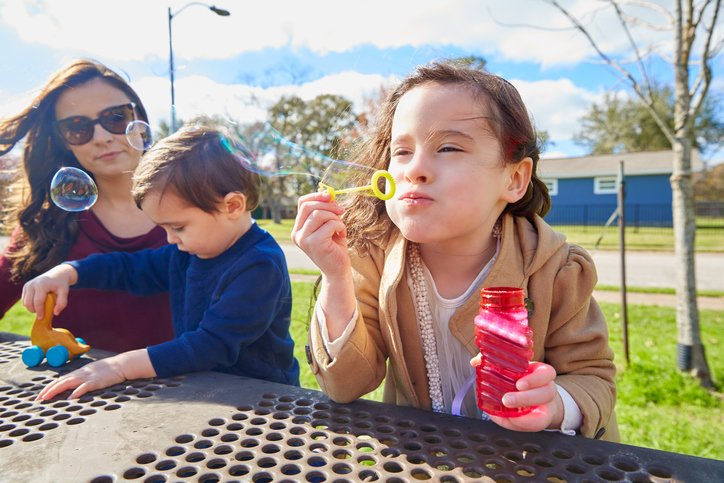 Mother daughter and son at park blowing bubbles
