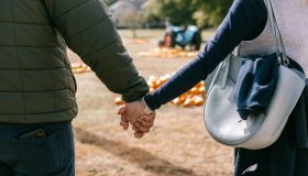 Couple holding hands at a pumpkin patch.