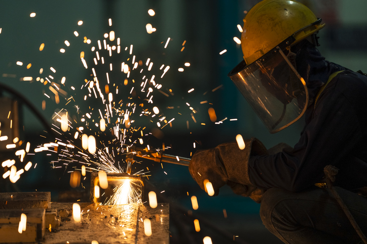 Welder welding steel in workshop.