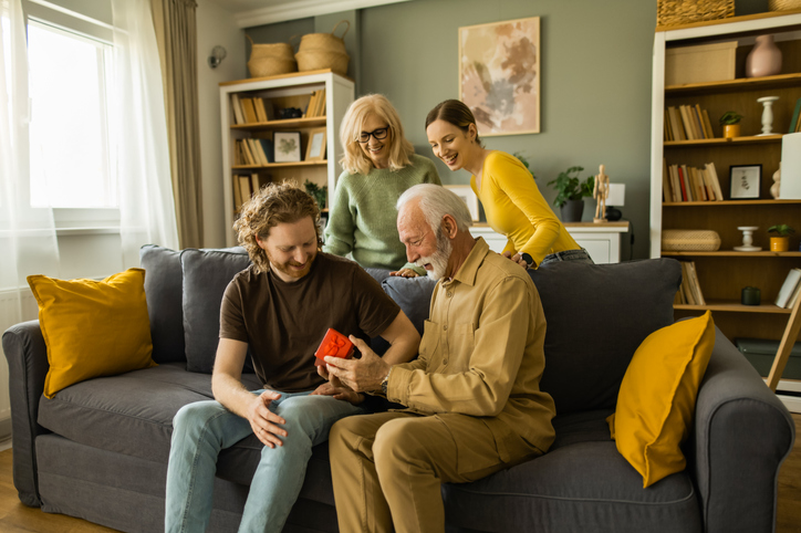 Multigenerational family celebrating grandfather's birthday with gift