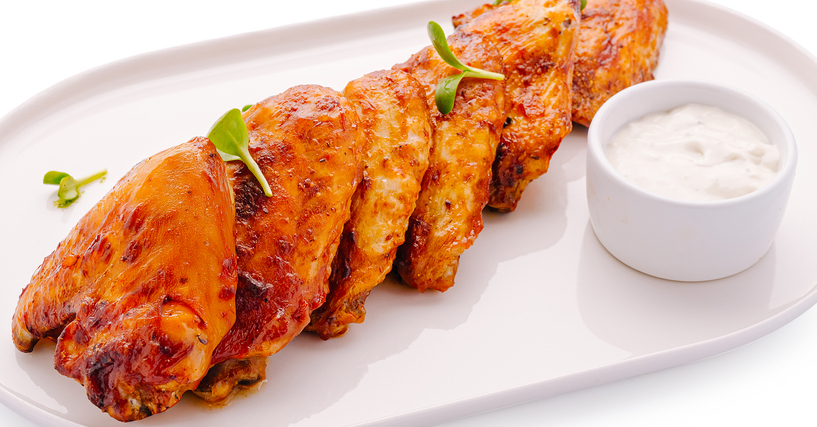 Crispy baked chicken wings with ranch dressing on white plate