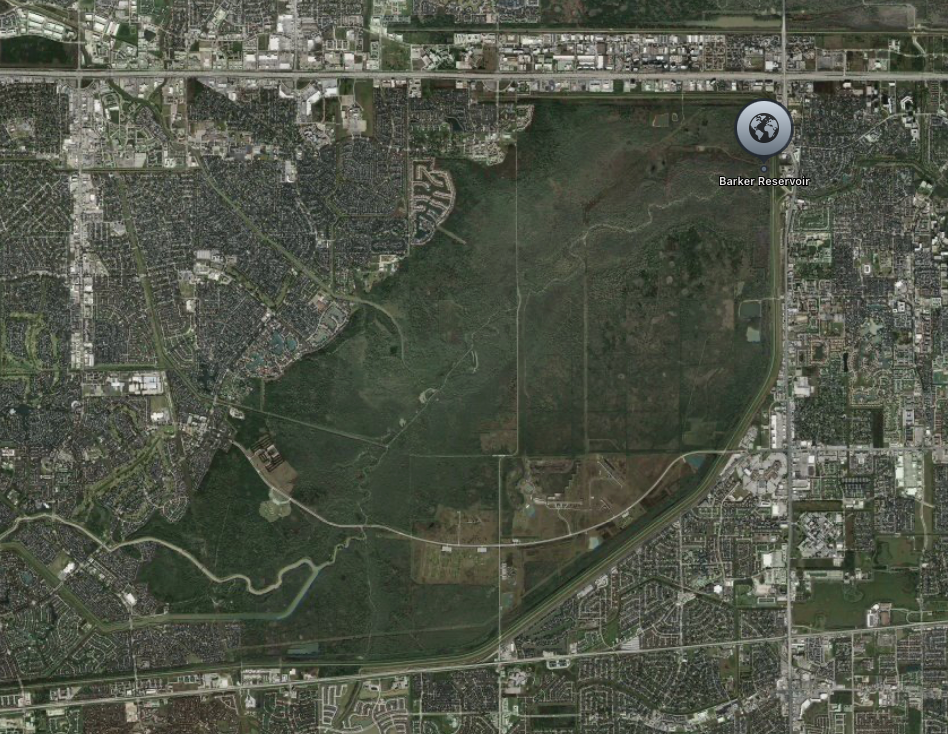 Aerial view of a suburban area with a large reservoir, surrounded by residential and commercial development.