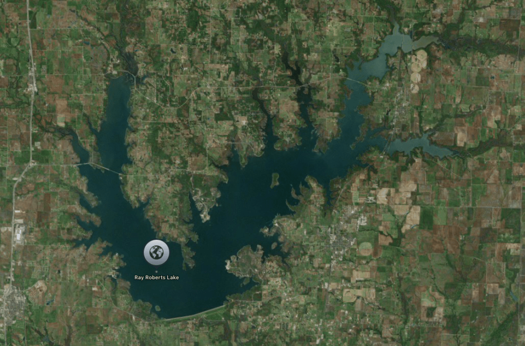 Aerial view of Ray Roberts Lake surrounded by rural landscape with agricultural fields and wooded areas.