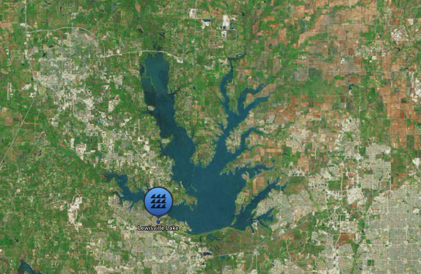 Aerial view of Lewisville Lake, a large body of water surrounded by green vegetation and some urban development.