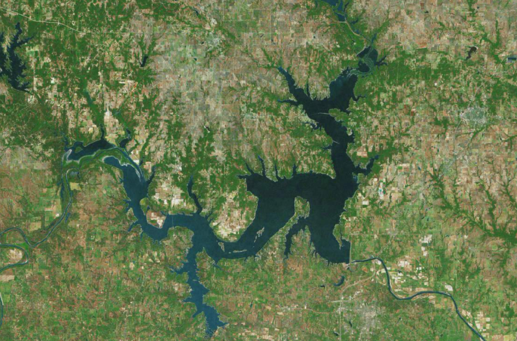 Aerial view of a large lake surrounded by wooded and agricultural areas.