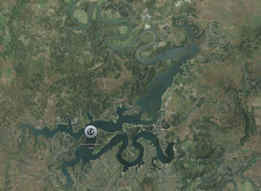 Aerial view of Possum Kingdom Lake, a large body of water surrounded by green, hilly terrain.